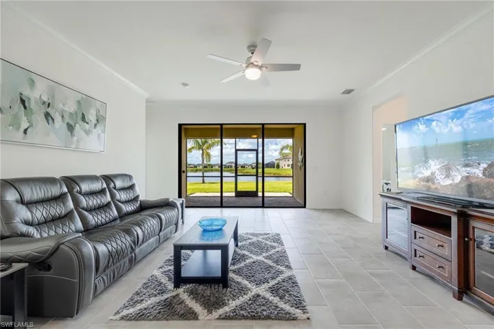 Living room featuring ornamental molding, ceiling fan, and light tile floors