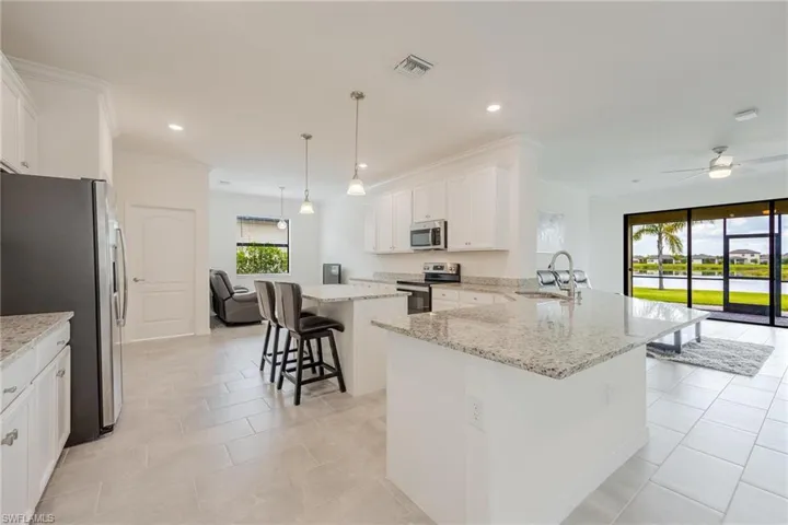 Kitchen featuring decorative light fixtures, stainless steel appliances, ceiling fan, a breakfast bar area, and a center island