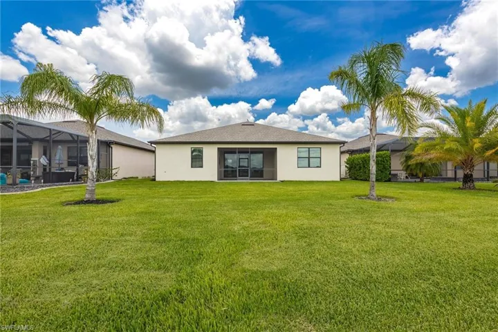 Rear view of house featuring a lawn and a lanai