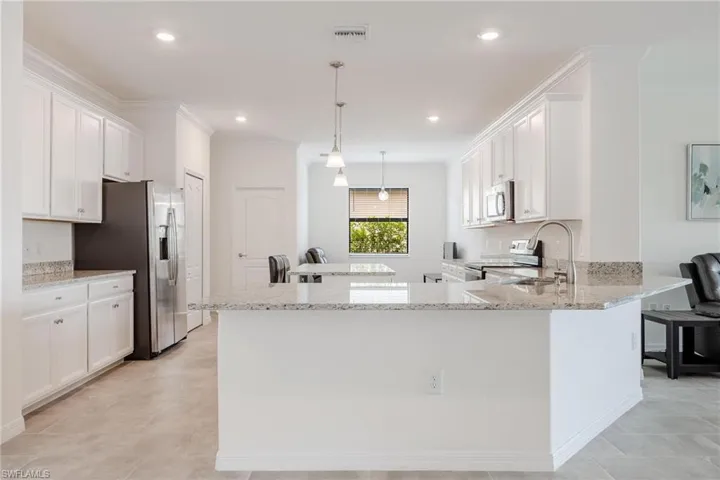 Kitchen featuring hanging light fixtures, light tile floors, white cabinets, and appliances with stainless steel finishes