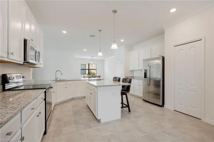 Kitchen featuring a kitchen breakfast bar, appliances with stainless steel finishes, light tile floors, and a kitchen island
