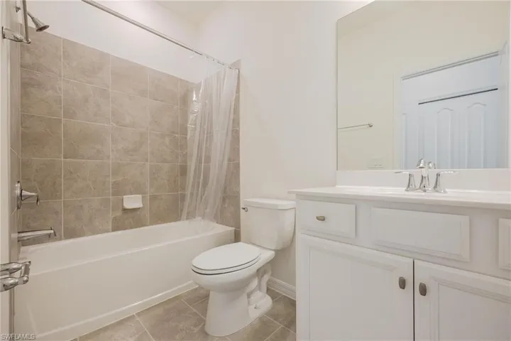Full bathroom with tile flooring, shower / bath combo, toilet, and vanity