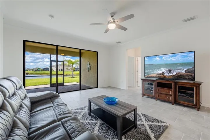 Living room with ornamental molding, light tile flooring, ceiling fan, and a water view