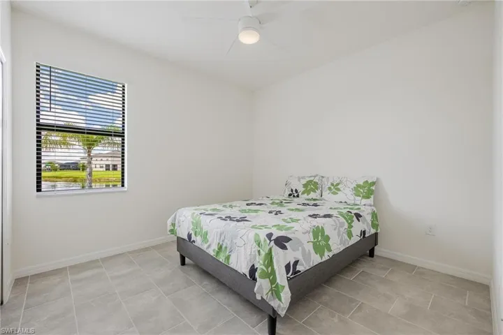 Bedroom with ceiling fan and light tile floors