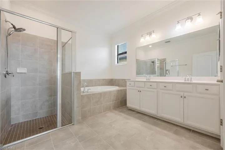 Bathroom with tile floors, separate shower and tub, dual sinks, and vanity with extensive cabinet space