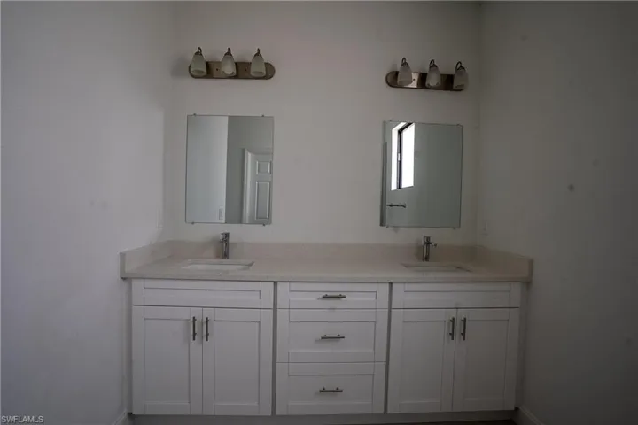 Dual vanity featuring white shaker-style cabinetry, a light-toned countertop, and undermount sinks