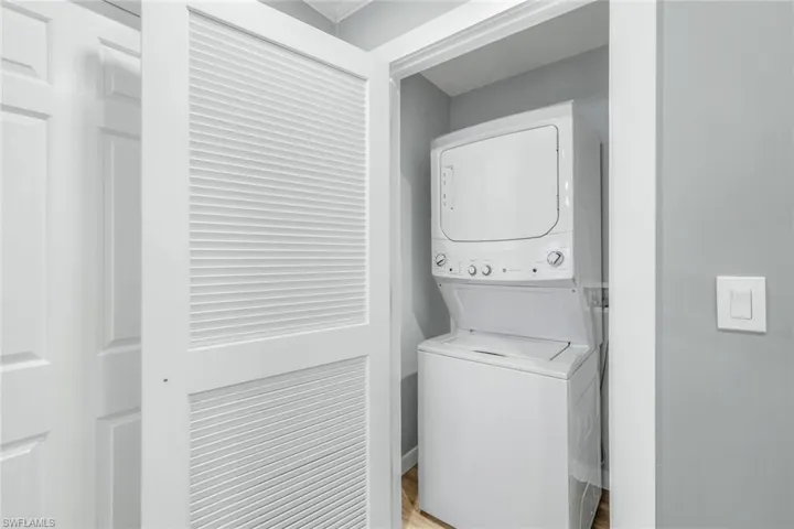 Laundry room with stacked washer / drying machine and light wood-type flooring