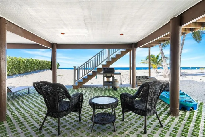 View of patio / terrace with view of water and beach, area for grilling, and stairs