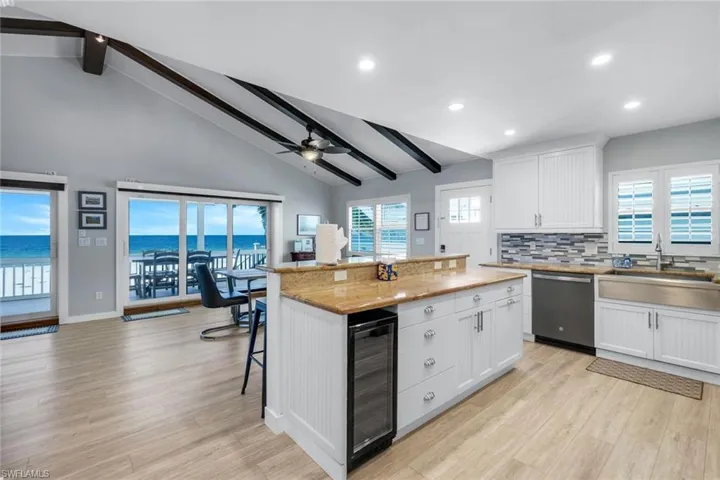 Kitchen featuring beamed ceiling, white cabinetry, backsplash, healthy amount of natural light, and high vaulted ceiling