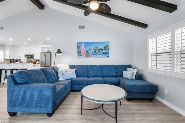 Living room featuring beamed ceiling, light wood-type flooring, and high vaulted ceiling