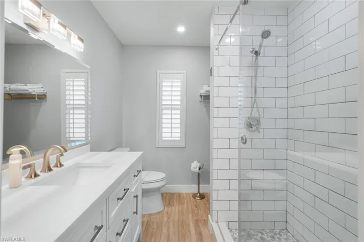 Full bath with vanity, a walk in shower, light wood-style floors, and recessed lighting