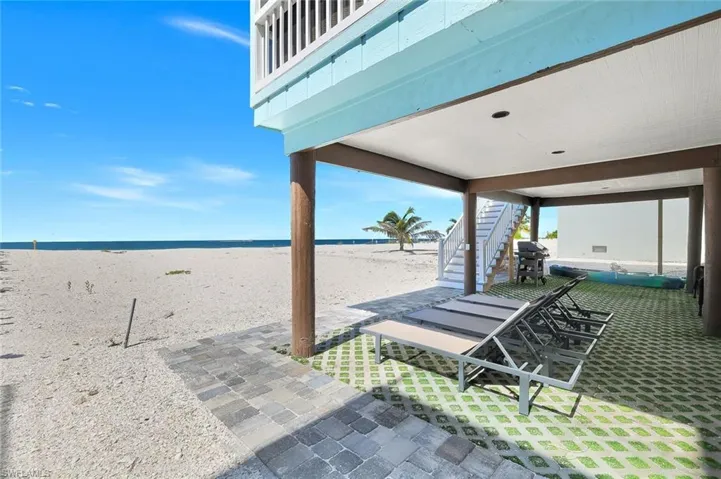 View of patio / terrace with stairs, grilling area, and view of water and beach