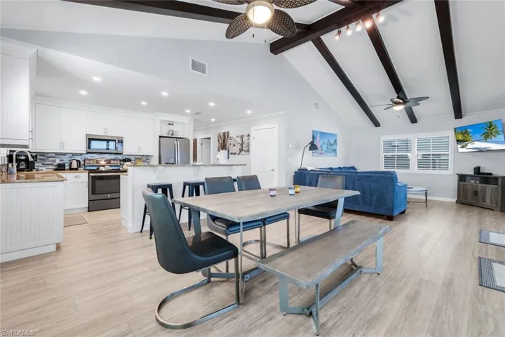 Dining space featuring beam ceiling, ceiling fan, high vaulted ceiling, light wood finished floors, and recessed lighting