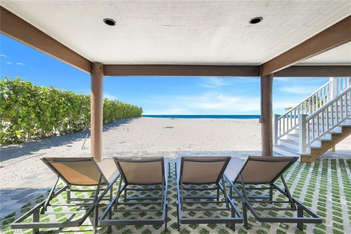 View of patio featuring view of water and beach and stairs