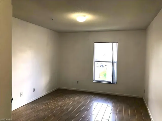 Unfurnished room with dark wood-style flooring and baseboards