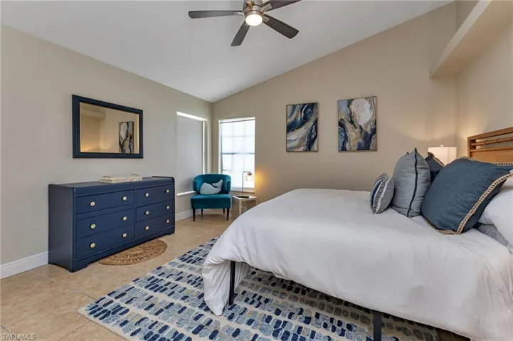 Tiled bedroom featuring ceiling fan and vaulted ceiling
