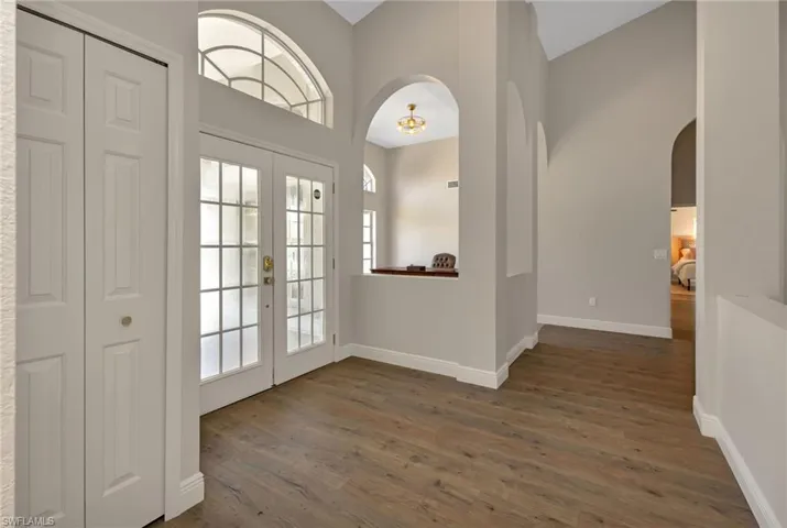 Doorway to outside with dark wood-type flooring, french doors, and high vaulted ceiling