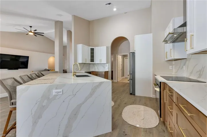 Kitchen with sink, white cabinetry, light stone counters, and light hardwood / wood-style floors