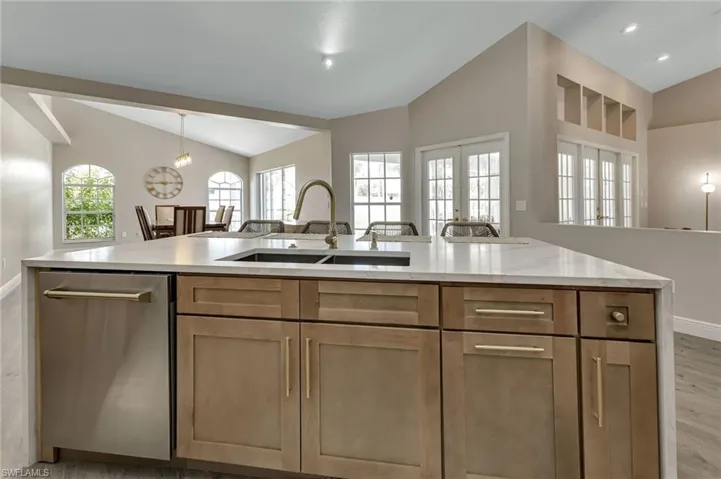 Kitchen with lofted ceiling, light wood-type flooring, dishwasher, a healthy amount of sunlight, and sink