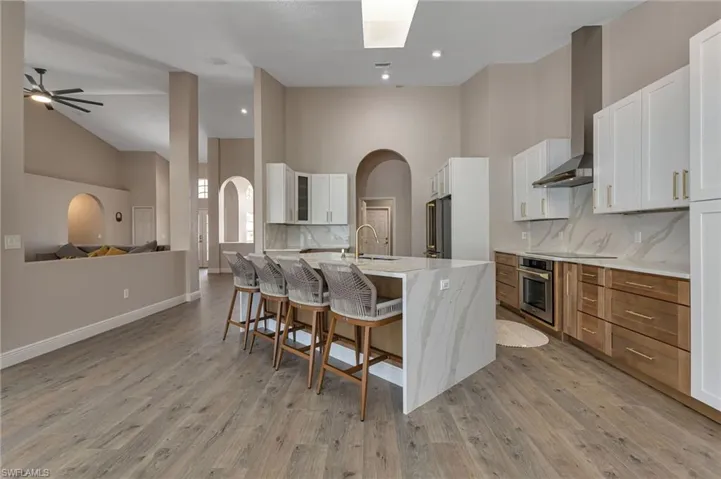 Kitchen with white cabinetry, high vaulted ceiling, and backsplash
