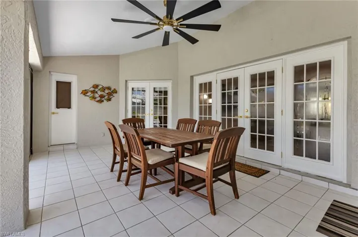 Tiled dining room featuring vaulted ceiling, french doors, and ceiling fan
