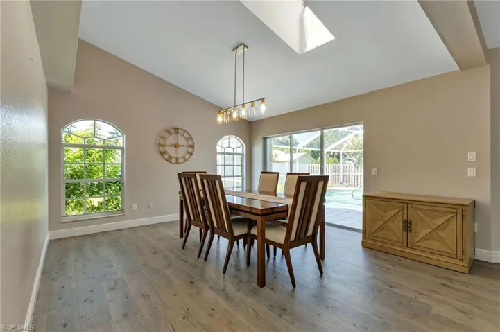 Dining area with a notable chandelier, high vaulted ceiling, a wealth of natural light, and hardwood / wood-style floors