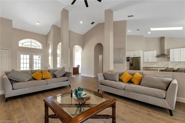 Living room with light hardwood / wood-style flooring, ceiling fan, and high vaulted ceiling