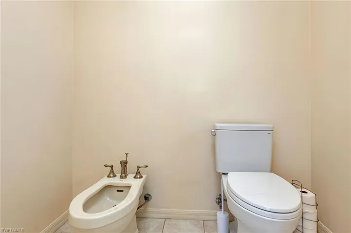 Bathroom with a bidet, toilet, and tile patterned floors