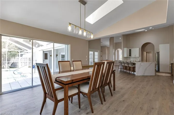 Dining area featuring light hardwood / wood-style floors, sink, a healthy amount of sunlight, and high vaulted ceiling