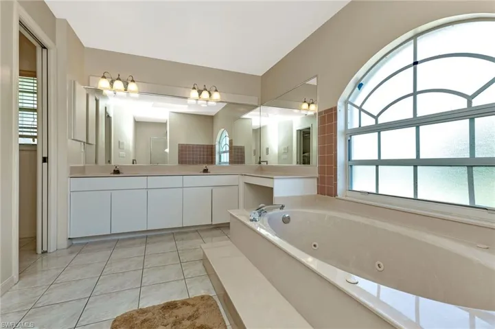 Bathroom featuring a bathing tub, tile patterned flooring, and double sink vanity
