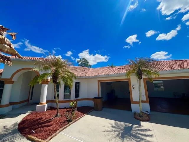 View of front facade featuring a tile roof, an attached garage, driveway, and stucco siding