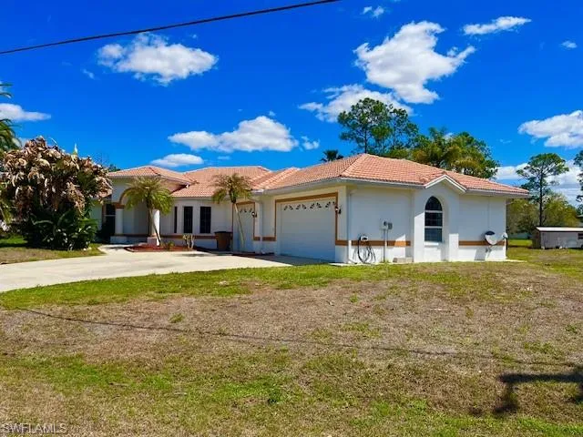 View of front facade featuring a garage, a tile roof, concrete driveway, a front lawn, and stucco siding