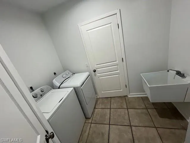 Laundry area featuring light tile patterned floors and washer and clothes dryer