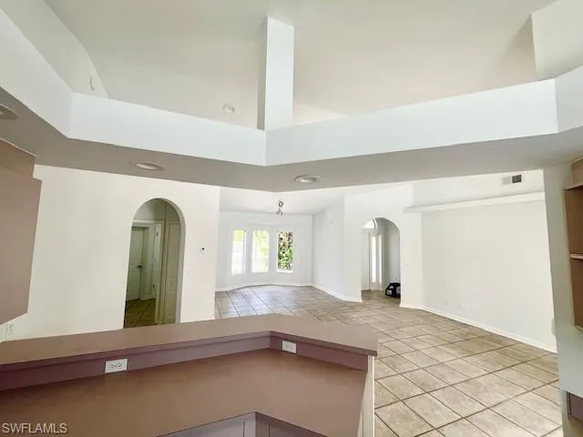 Empty room with light tile patterned flooring and arched walkways