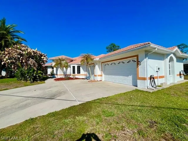 Single story home featuring an attached garage, driveway, stucco siding, a tiled roof, and a front yard