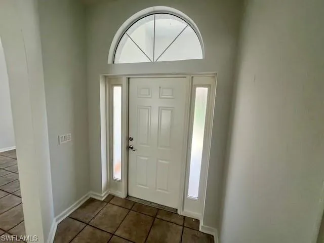 Foyer entrance with baseboards and dark tile patterned flooring