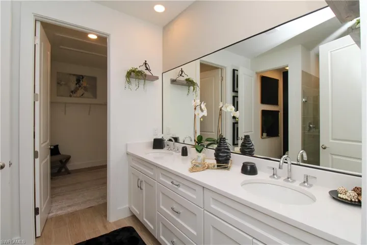 Full bathroom featuring double vanity, a spacious closet, light wood finished floors, a shower stall, and recessed lighting