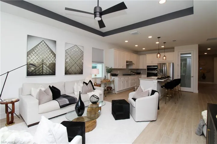 Living area featuring a tray ceiling, wood tiled floors, ceiling fan, and recessed lighting