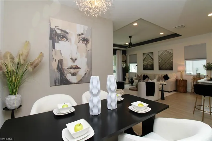 Dining room with hanging lights, a tray ceiling, plenty of natural light, wood finished floors, and a ceiling fan