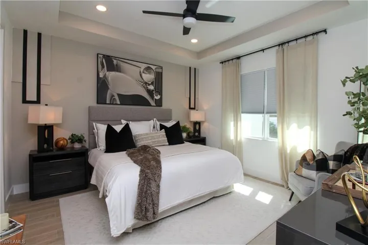 Bedroom featuring a raised ceiling, recessed lighting, ceiling fan, and light wood finished floors