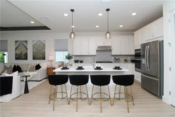 Kitchen with stainless steel appliances, hanging light fixtures, a breakfast bar, and white cabinetry