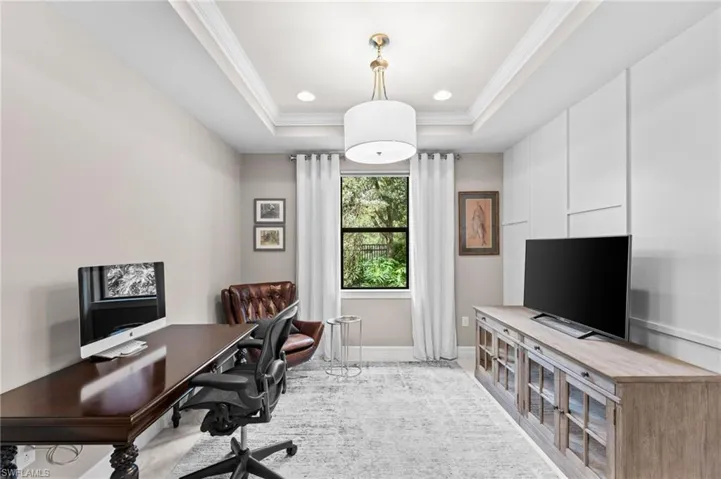 Office space featuring crown molding, light colored carpet, and a tray ceiling