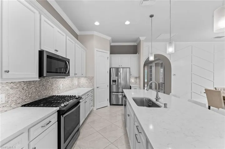 Kitchen with white cabinets, stainless steel appliances, sink, and hanging light fixtures