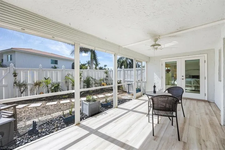 The large covered screened patio has wood plank tile flooring and manual roll down hurricane shutters