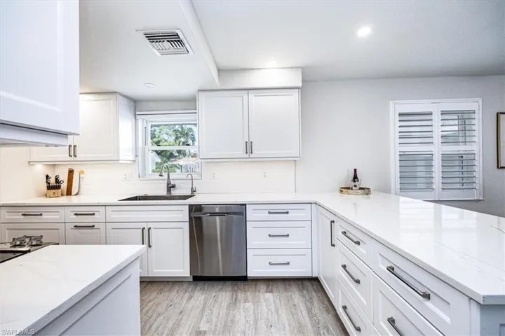 Kitchen featuring white cabinetry, quartz countertops, single bowl sink, stainless steel dishwasher
