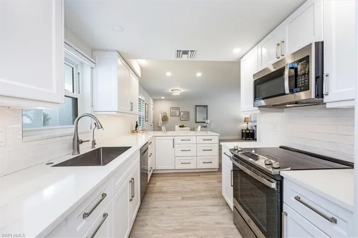 Kitchen featuring white cabinetry, front knob control slide in oven, single bowl sink and microwave