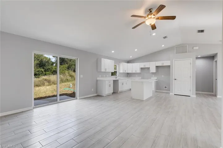 Unfurnished living room featuring vaulted ceiling, a ceiling fan, light wood-type flooring, and recessed lighting
