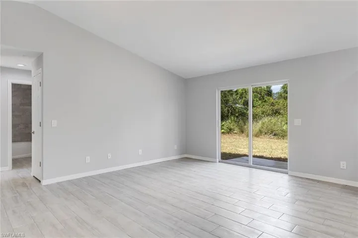 Unfurnished room featuring light wood-style flooring and vaulted ceiling