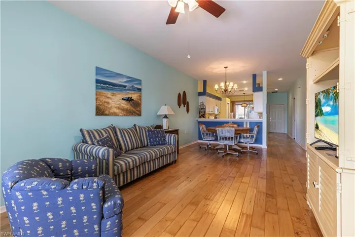 Living area with light wood-style floors, ceiling fan, and a chandelier