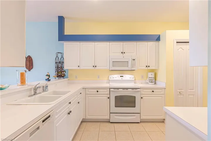Kitchen with white appliances, white cabinets, light countertops, and light tile patterned floors